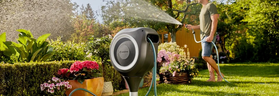 Person bewässert Garten mit Gartenschlauch